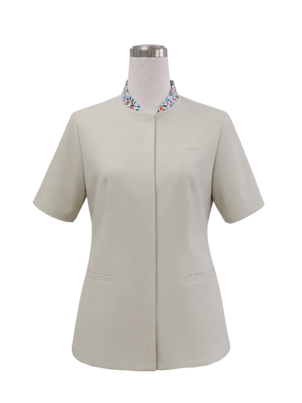 Women's short-sleeve corporate tunic top in neutral beige featuring a standing mandarin collar with a colorful floral inner trim and concealed button placket, designed by Modoleen Singapore for receptionist, clinic, and spa uniform programs.