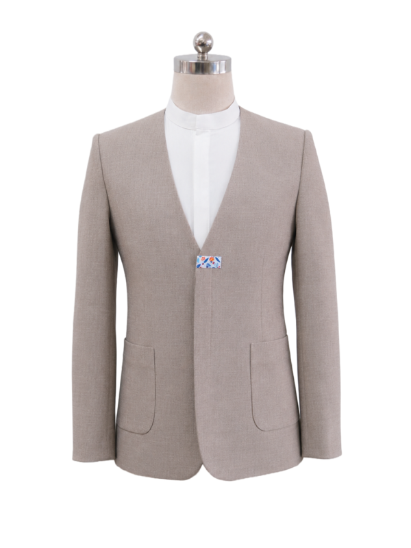 Men's collarless corporate suit jacket in light tan beige featuring a deep round V-cut neckline, single center floral bow-tie clasp fastener, and front patch pockets, designed by Modoleen Singapore for luxury hospitality, spa, and wellness uniform programs.