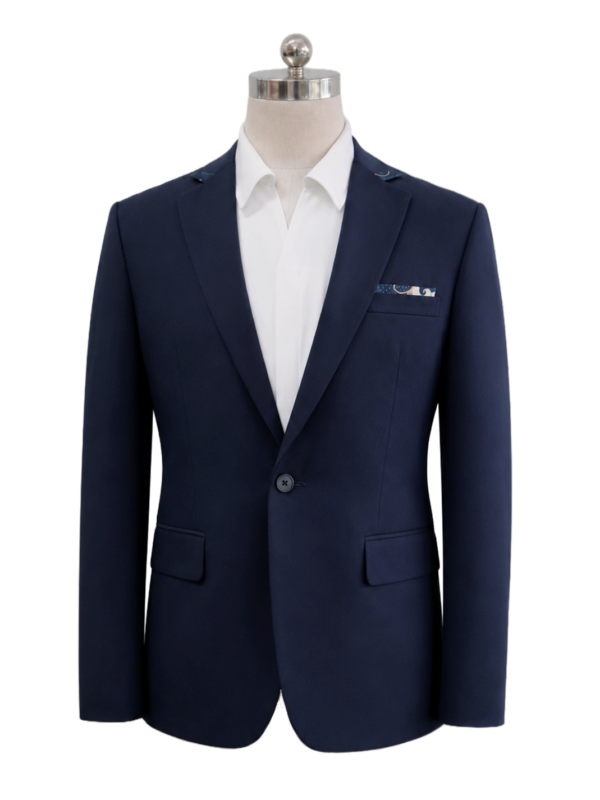 Men's classic single-button corporate suit blazer in dark navy blue featuring tailored notch lapels, side flap pockets, and a patterned pocket square accent, styled over an open-collar white shirt, designed by Modoleen Singapore for corporate leadership and hospitality uniform programs.